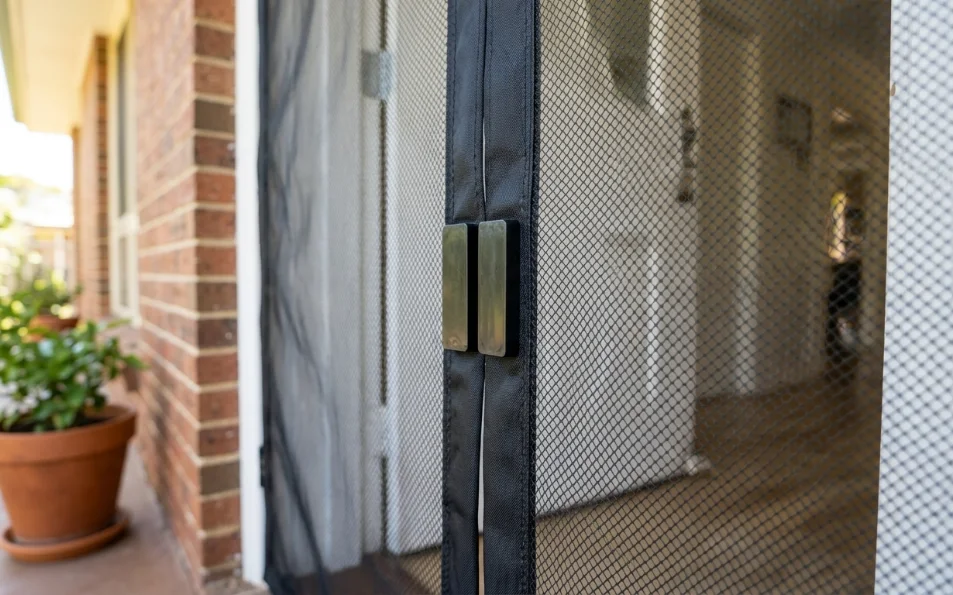 Detalle de la unión central con imanes en una mosquitera para puertas