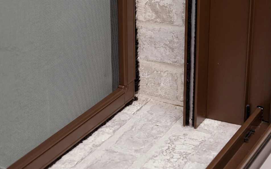 Detalle de mosquitera fija marrón con malla de fibra de vidrio a medida